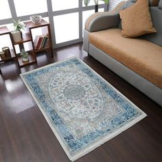 a living room filled with furniture and a rug on top of a hard wood floor