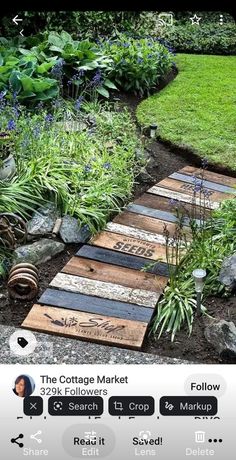 a wooden walkway made out of pallets in the middle of some grass and flowers