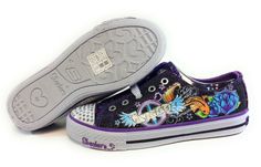 a pair of black and purple shoes with tattoos on the bottom, one shoe has white outs