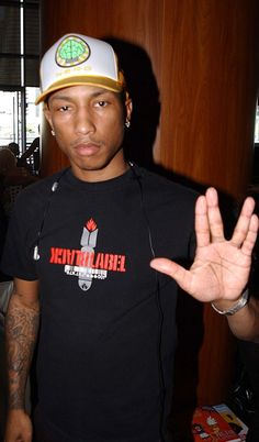 a man wearing a black shirt and hat making the vulcan sign