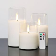 three lit candles with remote control on table