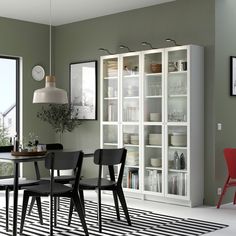 a dining room table and chairs in front of a bookcase with glass doors on it