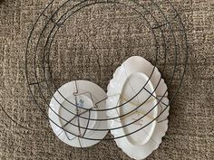 three plates are stacked in a wire basket on the floor next to a wall clock