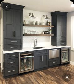 a kitchen with dark gray cabinets and white counter tops, wood flooring and open shelving