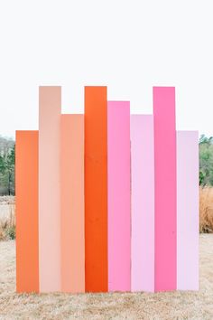 four different colored boards are standing in the middle of a grass field with trees and bushes behind them