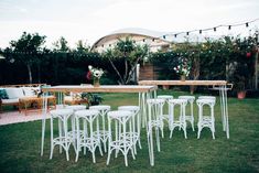 white chairs and tables are set up in the yard for an outdoor party with string lights