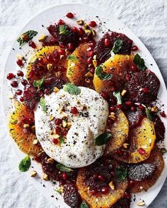 a white plate topped with oranges and pomegranate