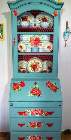 an old china cabinet painted in blue with flowers on the front and bottom, is shown