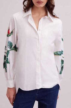 The FLOWERS shirt is the perfect way to show your appreciation for spring’s blooms. This lightweight tunic length shirt features a classic point collar and center button placket. The long sleeves are loose and gather at the French cuff that allow for cufflinks. The bottom hem is high low and features large scalloped edges. The sleeves also feature a single printed rose on each arm. This is a piece you will wear again and again! Tunic legth poplin shirt Classic point collar and center button plac Spring Daywear Blouse With Fold Down Collar, Spring Daywear Blouse With Roll-up Sleeves, Button Cuffs Shirt For Spring Workwear, Spring Workwear Shirt With Button Cuffs, Spring Workwear Blouse With Cuffs, Spring Blouse With Button Cuffs And Relaxed Fit, Spring Workwear Shirt With Cuff, Classic Long Sleeve Blouse With Floral Print, Classic Long Sleeve Floral Print Blouse