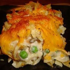 a casserole dish with peas and cheese on a black plate, ready to be eaten