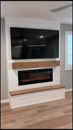 an empty room with a fireplace in the middle and a flat screen tv above it