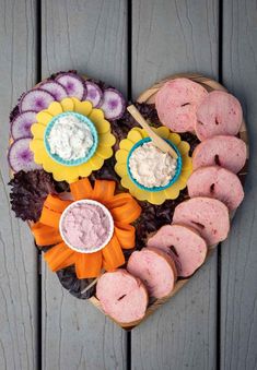 donuts arranged in the shape of a heart with dips and flowers on them