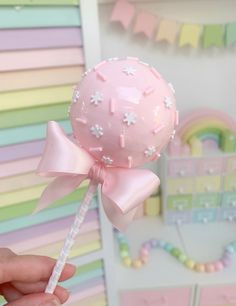 a hand holding a pink lollipop with stars on it