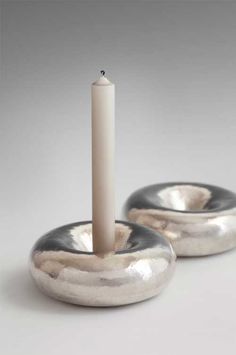 two silver candle holders sitting on top of each other