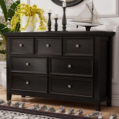 a black dresser with two candles on top and a clock in the corner behind it