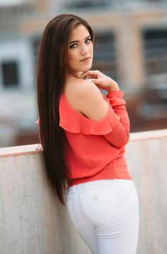 a beautiful young woman leaning against a wall