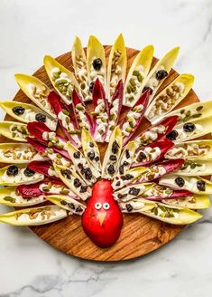 a wooden platter filled with fruit and veggies shaped like a peacock's head