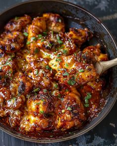 a skillet filled with chicken covered in sauce and garnished with parsley