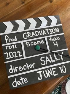 a black and white graduation sign sitting on top of a wooden table next to a cup