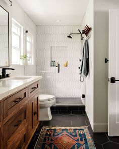 a bathroom with black and white tile flooring, wooden cabinets and a rug on the floor