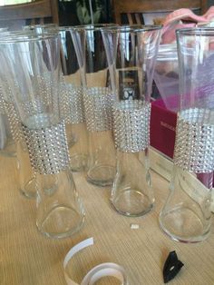 several clear glass vases sitting on top of a table next to a ribbon and other items