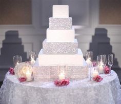 a white wedding cake sitting on top of a table next to wine glasses and candles