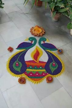 a colorful rangolite design on the ground in front of some potted plants