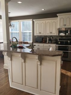 a large kitchen with white cabinets and granite counter tops, along with an island in the middle