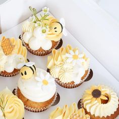 cupcakes decorated with yellow and white frosting are arranged in a square box