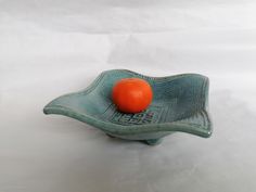 an orange sitting on top of a green bowl