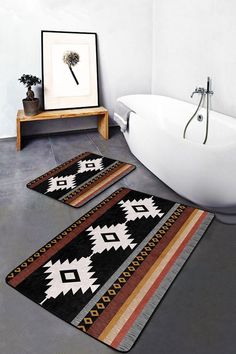 three bathroom rugs on the floor in front of a bathtub