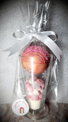 a cupcake is wrapped in plastic and has pink frosting on the top with white sprinkles