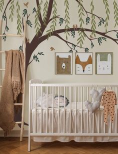 a baby's room with a tree wall decal and pictures on the wall