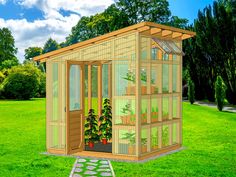 a small wooden greenhouse in the middle of a grassy field with trees and bushes around it