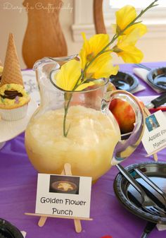 a pitcher filled with liquid sitting on top of a table next to plates and cupcakes