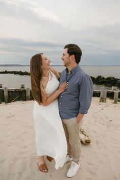 a man and woman are standing on the beach