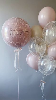 some balloons that are in the air with ribbons on them and one balloon has a name written on it