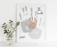 a baby's handprint is displayed next to a vase with flowers in it