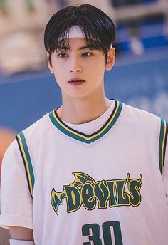 a young man wearing a jersey with the word devil's on it, standing in front of a basketball court