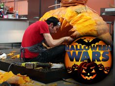 a man sitting on top of a table next to a giant pumpkin