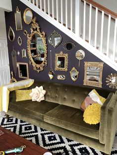 a living room filled with furniture and lots of mirrors on the wall next to a stair case