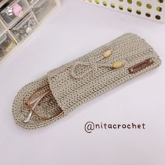 a crocheted purse with eyeglasses on it sitting on a table next to other items