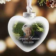 an ornament shaped like a heart with a photo on it hanging from a tree