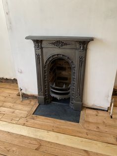 an old fireplace in the corner of a room with wood flooring and white walls