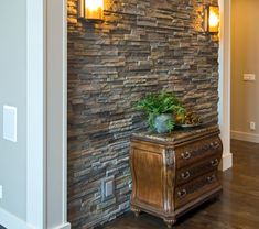 a stone wall with two lights and a plant on the end table in front of it