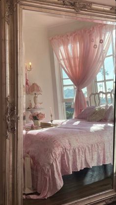 a large mirror reflecting a pink bed in a room