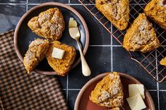 two plates filled with muffins and butter on top of a black tile floor