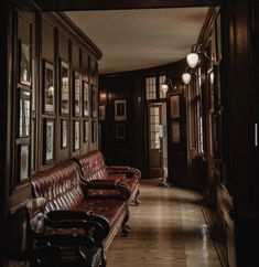 a long hallway with leather couches and framed pictures on the walls