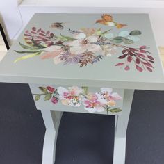 a painted side table with flowers on it