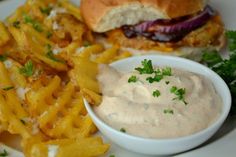 a white plate topped with french fries and a sandwich next to a bowl of dip